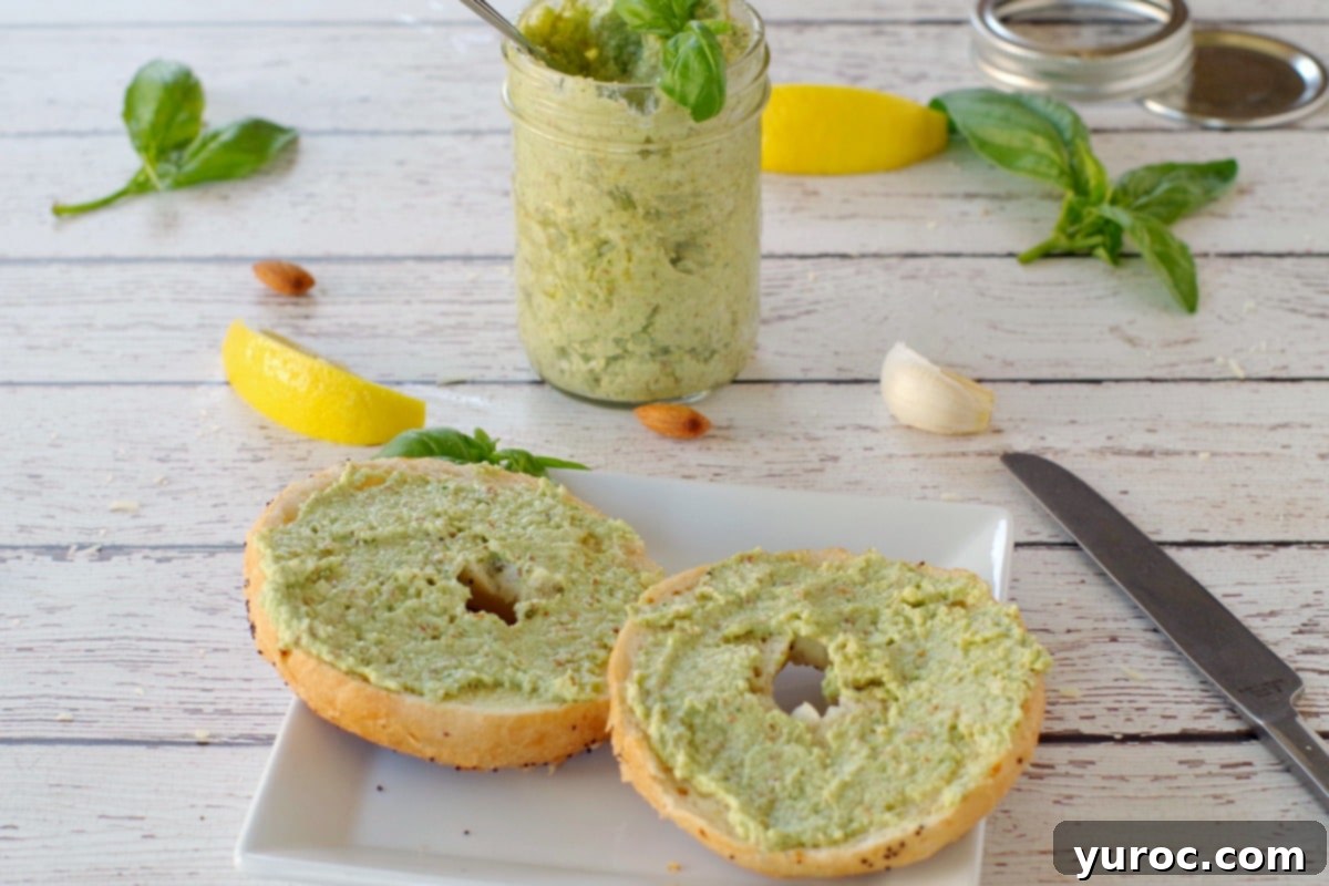 basil almond pesto on bagel with a jar of pesto in the background