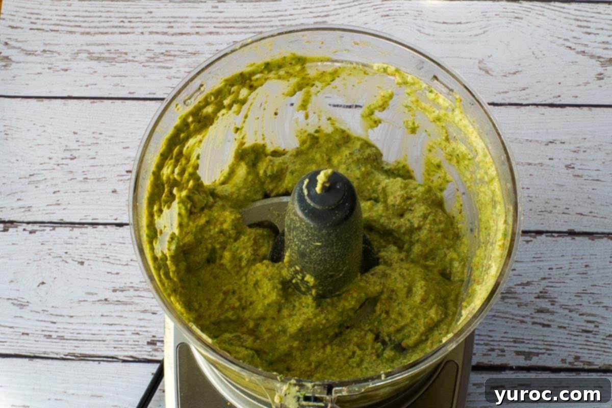 Basil pesto blended in bowl of food processor.