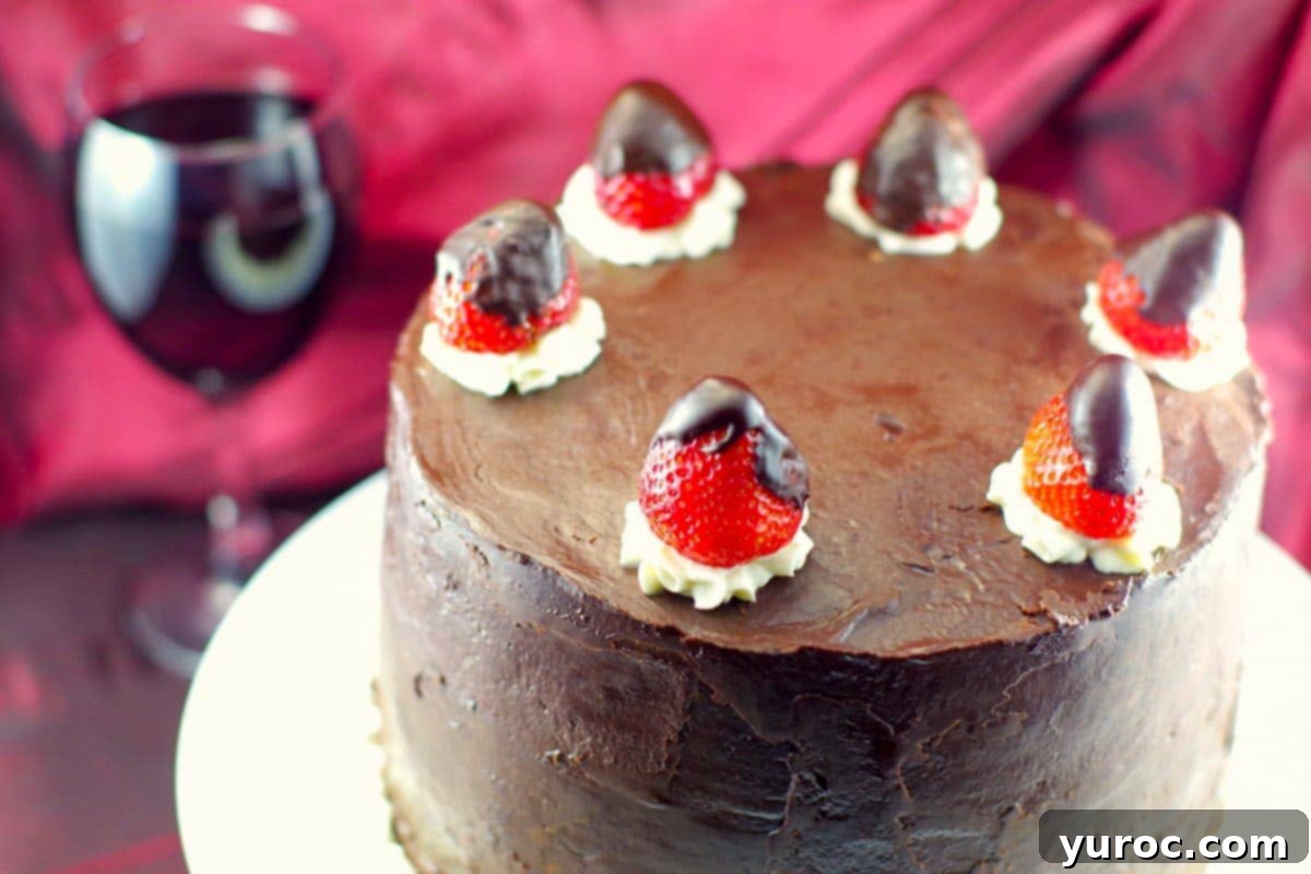 An overhead view of the Red Wine Chocolate Strawberry cake, beautifully presented with a glass of red wine in the background, highlighting its rich ganache.