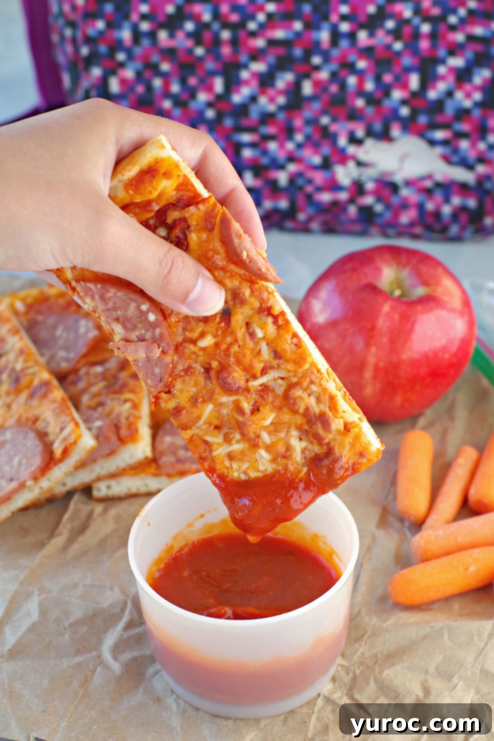 15 No-Prep Healthy School Lunches for Teens 3 pizza dipper being dipped into pizza sauce with pieces, an apple, carrots and lunch bag in background.
