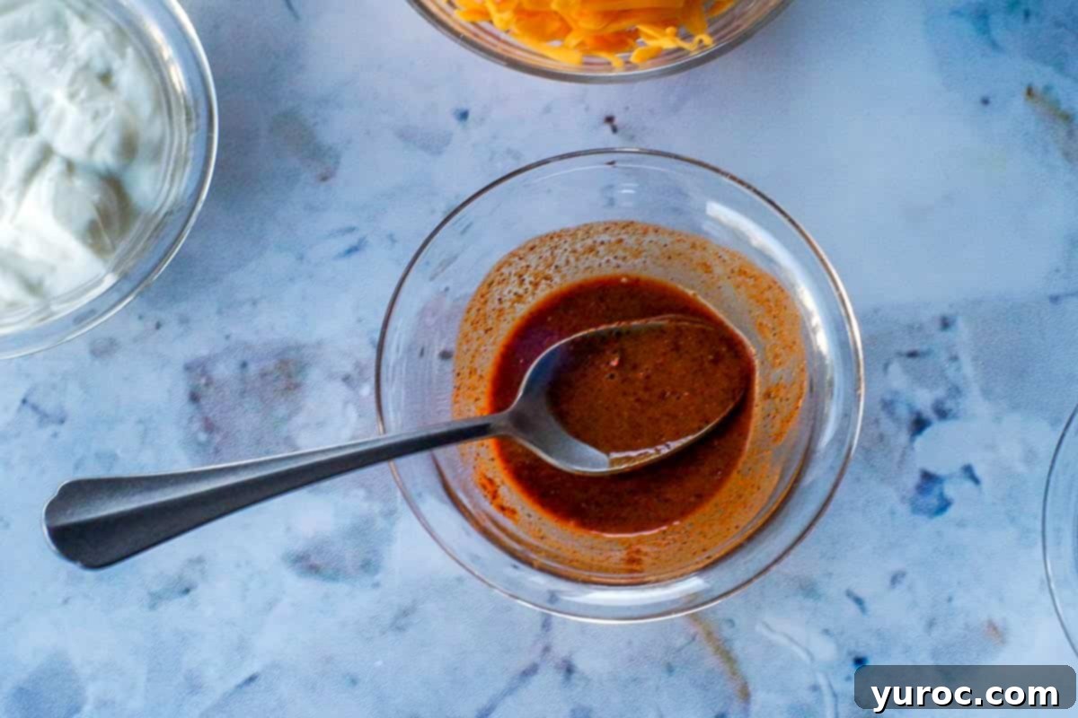 Taco seasoning and hot water mixed into a paste in a small glass bowl with a spoon.