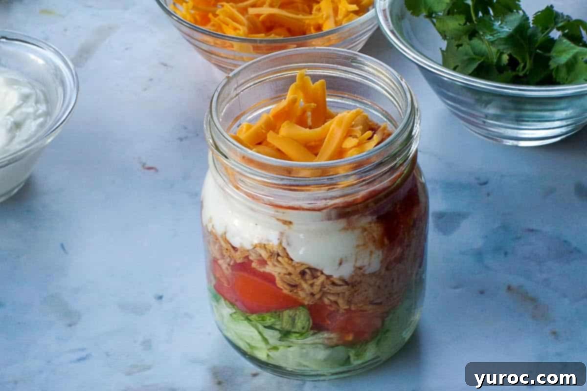Grated cheese being added to chicken taco salad.