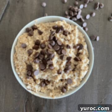 overhead view of chocolate chip cookie dough overnight oatmeal in a white bowl on wooden surface