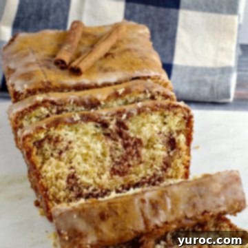 cinnamon loaf on marble cutting board with blue and white checkered tea towel in background