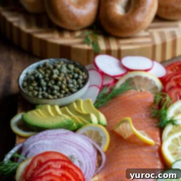 bagels in background with bagel toppings (salmon, veggies etc) on board in front