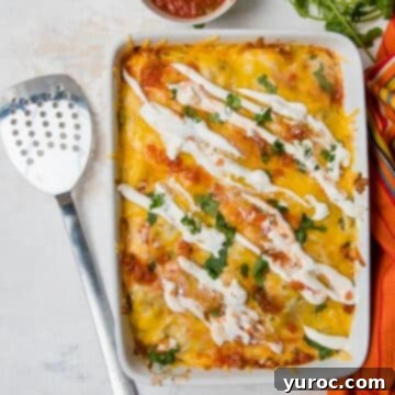 breakfast enchilada casserole in a white dish with a spatula beside it and salsa in the background
