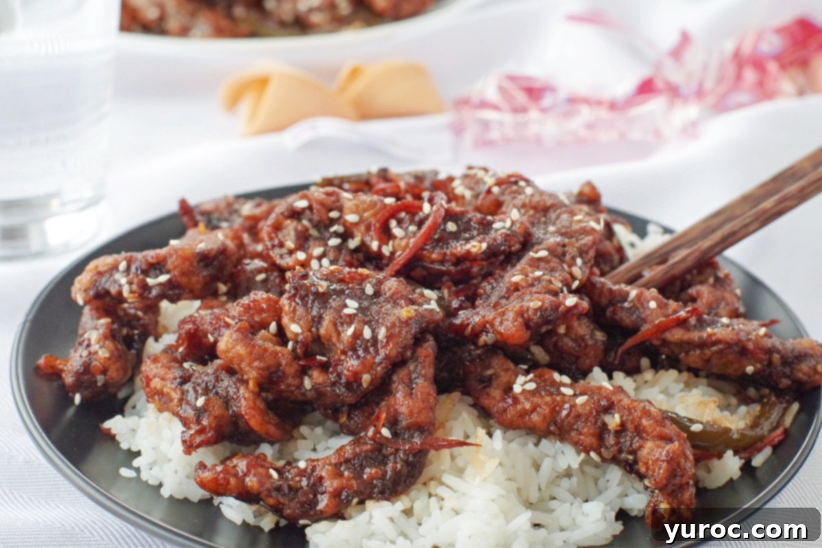 The Ultimate Calgary Ginger Beef 1 ginger beef over rice on a black plate on white table cloth, with fortune cookies