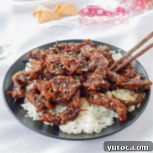 The Ultimate Calgary Ginger Beef 7 ginger beef over rice on a black plate with chopsticks