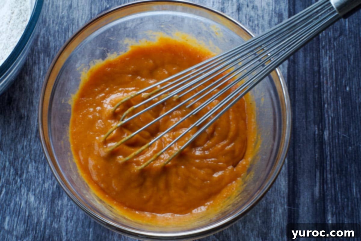 pumpkin sheet pan pancakes wet ingredients in a glass bowl with a whisk
