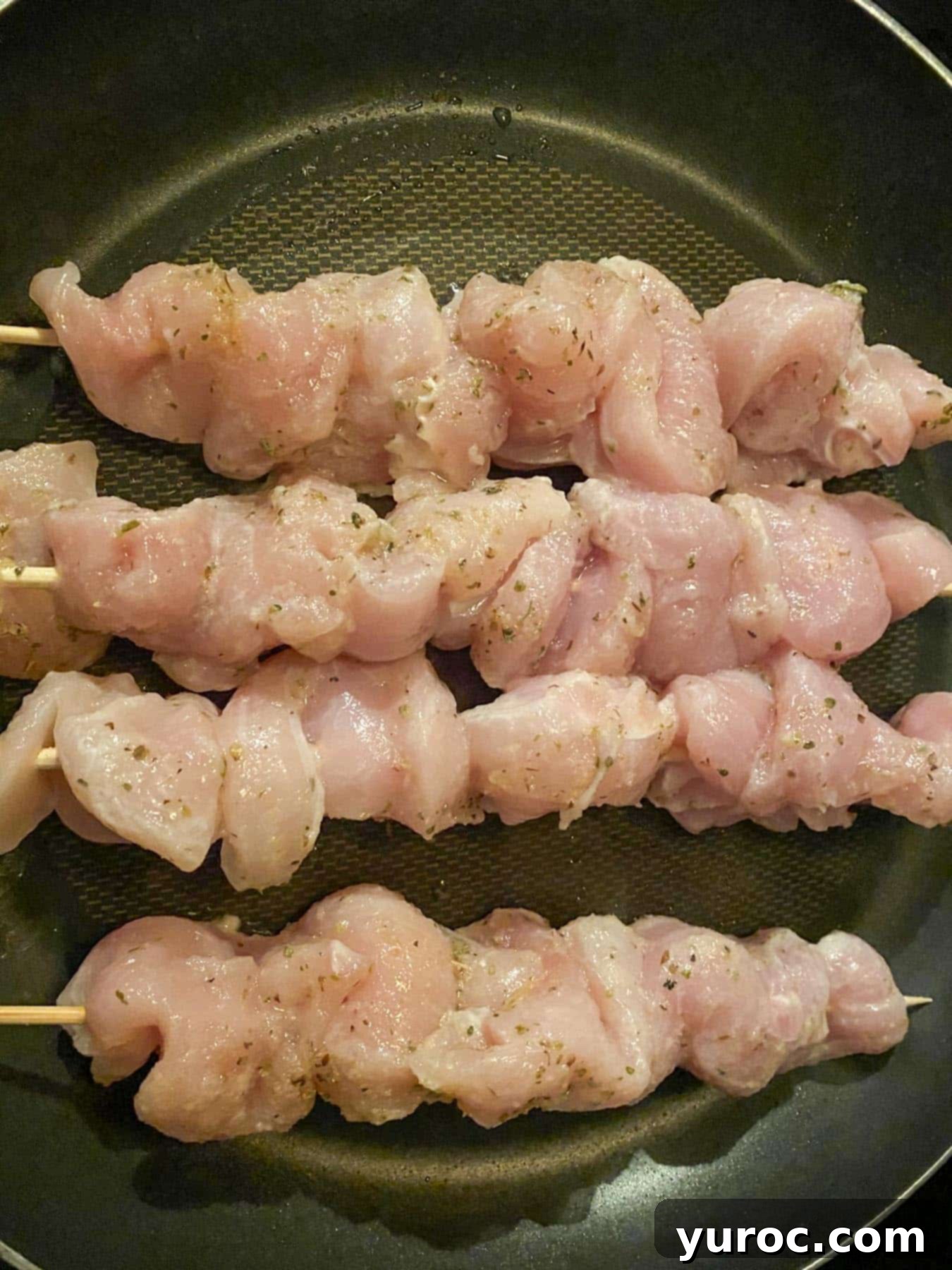 4 chicken souvlaki skewers in a frying pan