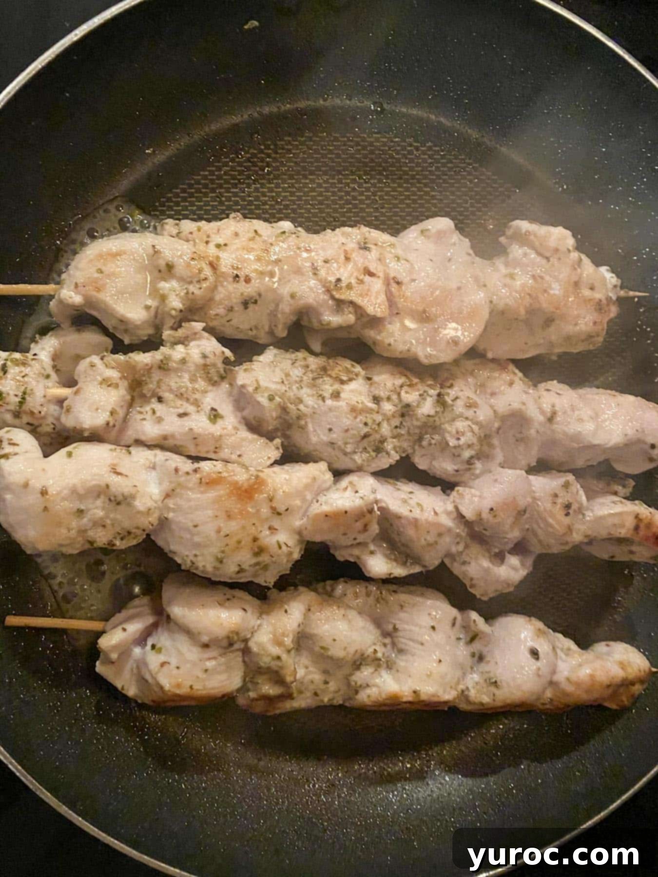 cooked chicken souvlaki skewers in a frying pan