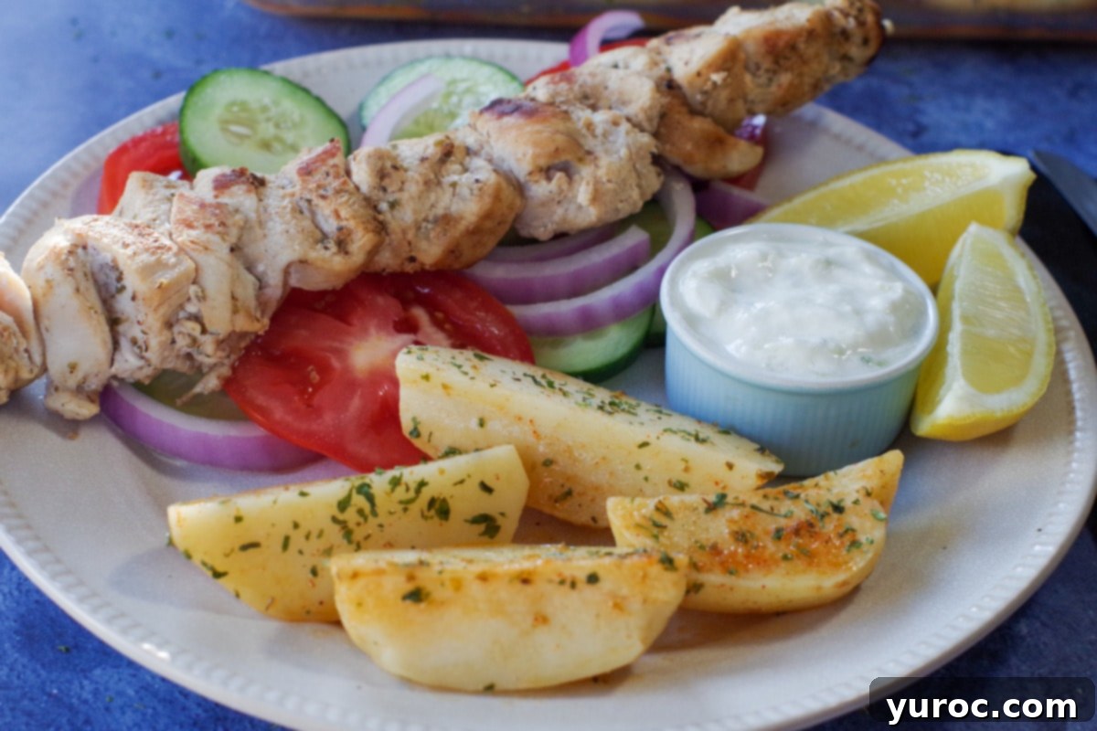 Greek chicken souvlaki on a bed of veggies with greek potatoes, lemon and tzatziki sauce