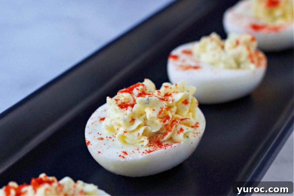 deviled egg with paprika sprinkled on top on black serving tray