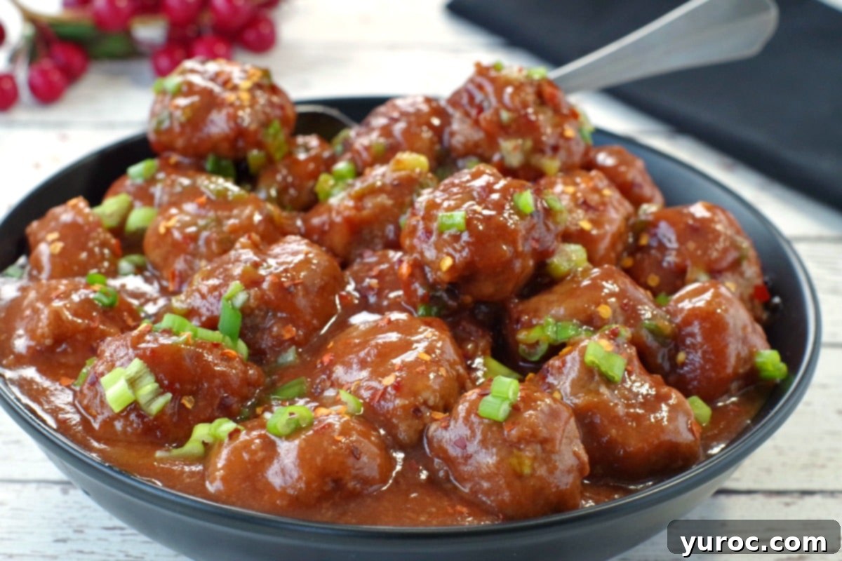 cranberry slow cooker turkey meatballs in a black bowl with a silver spoon