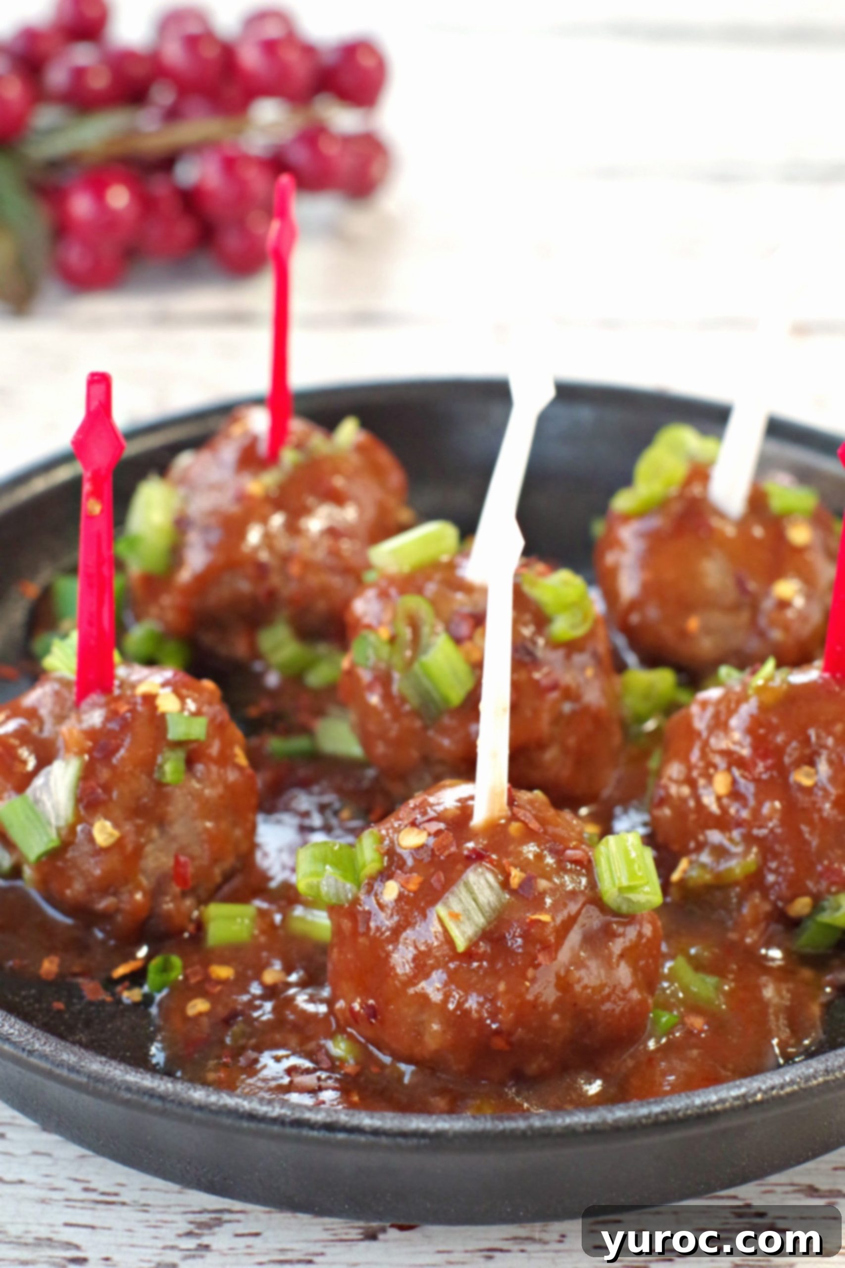 6 slow cooker turkey meatballs with red and white skewers on a black, round serving platter