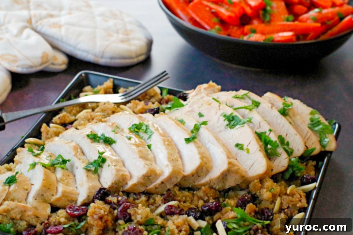 Sliced slow cooker turkey breast on a bed of cranberry quinoa dressing on a black platter, with a black bowl of roasted carrots and festive oven mitts in the background.