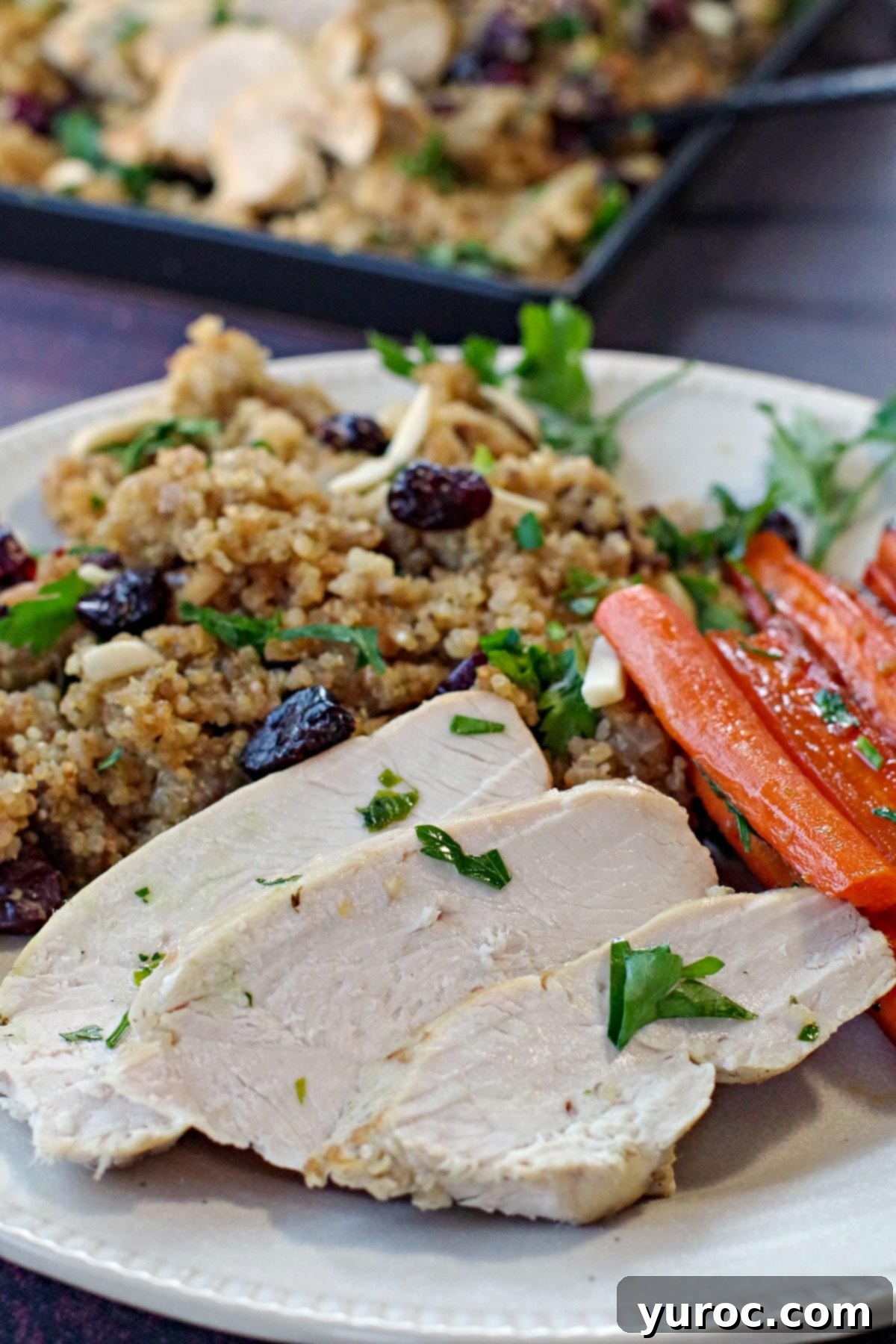 Slices of slow cooker boneless turkey breast on a white plate with glazed carrots and quinoa dressing.