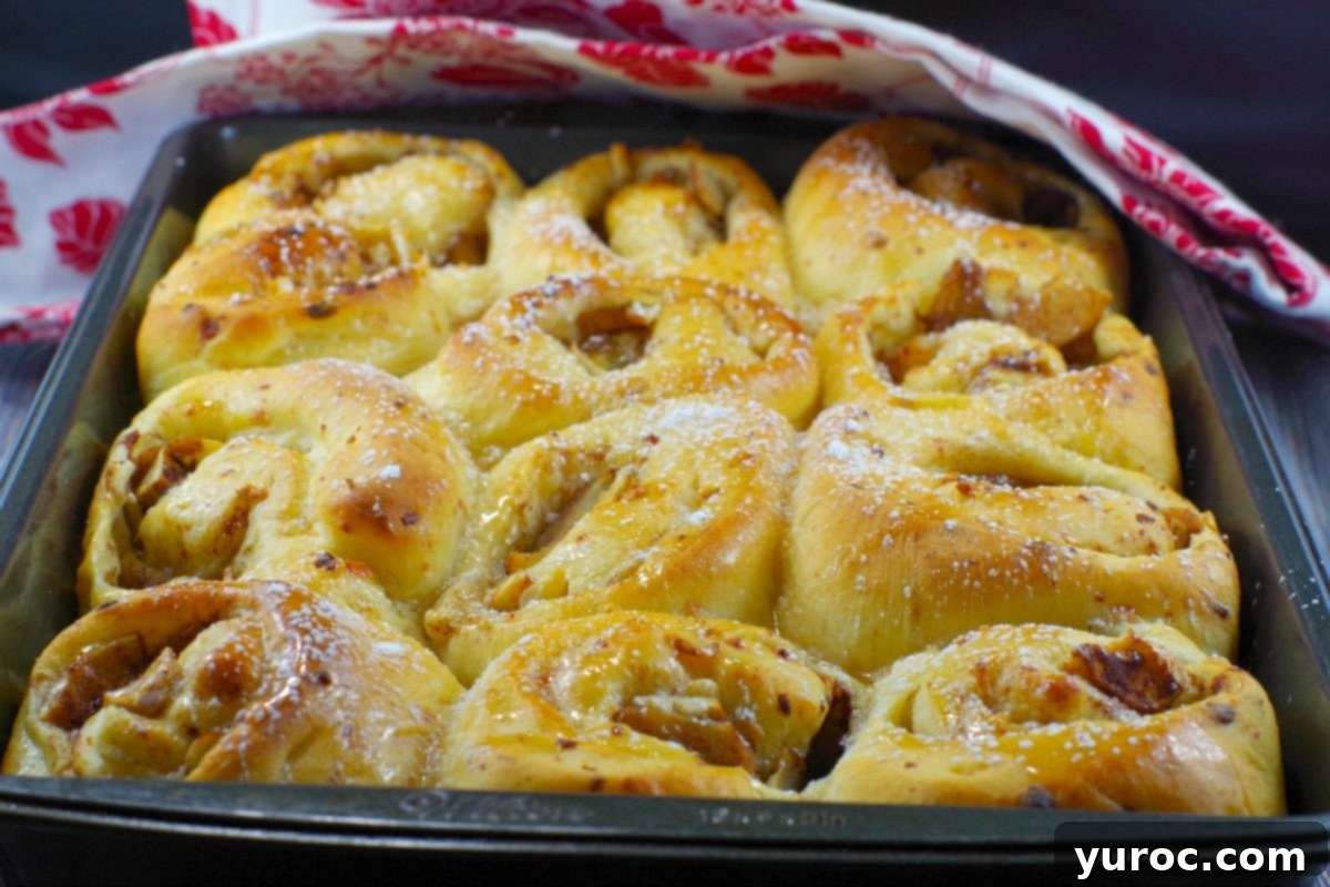 Freshly baked Bread Maker Apple Pie Cinnamon Rolls in a rectangular baking pan, golden brown and ready to be glazed.