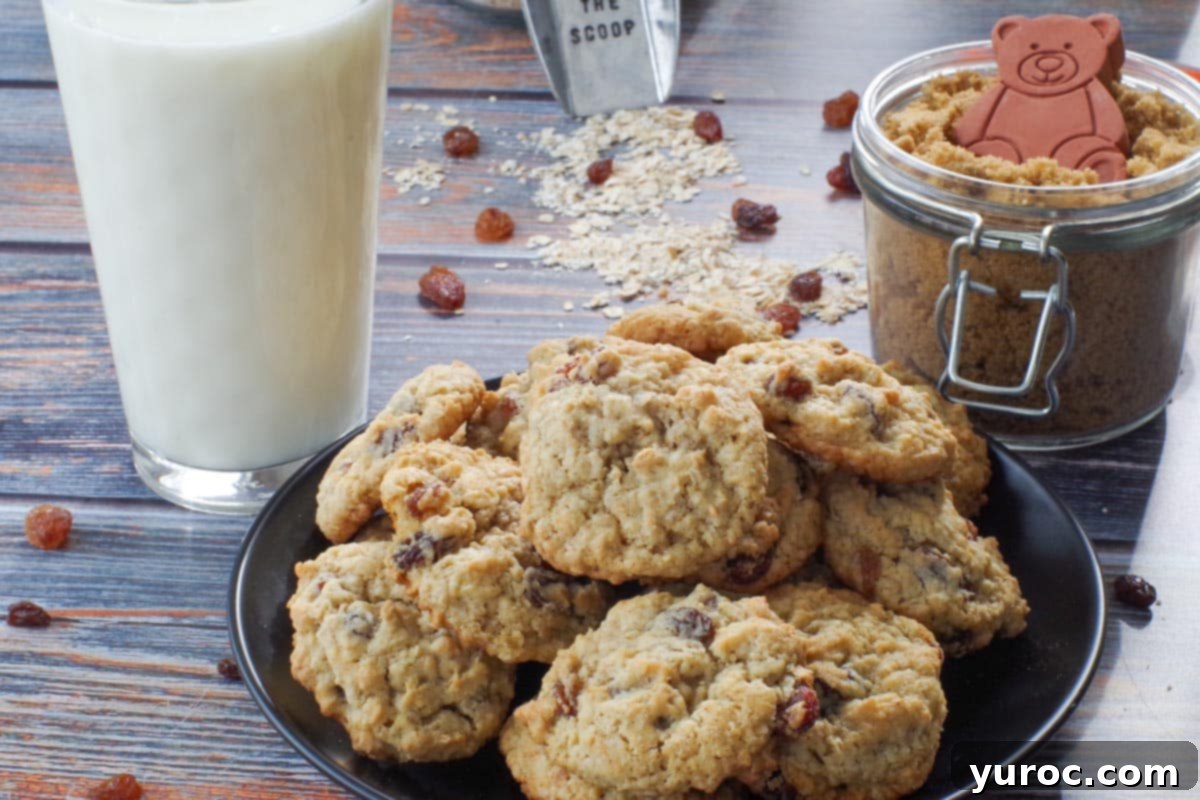 Easy oatmeal raisin cookies arranged on a black plate with a glass of milk and a jar of brown sugar in the soft-focus background.