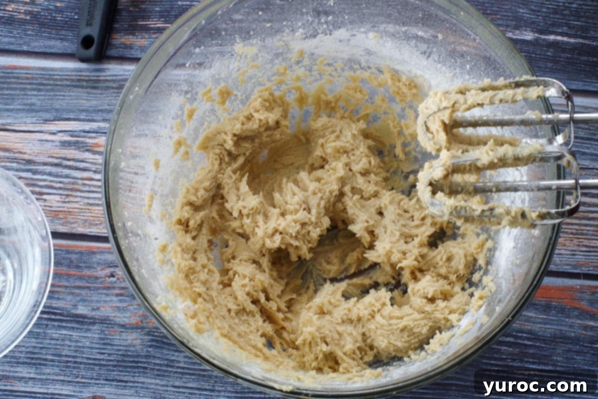 The combined dry ingredients (flour and baking soda) being added to the wet ingredients in a large glass bowl.