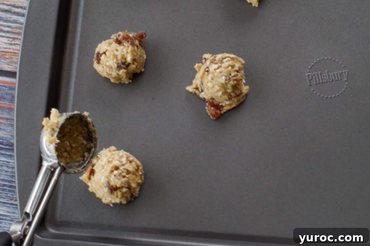Small balls of oatmeal raisin cookie dough dropped onto an ungreased cookie sheet, spaced apart.