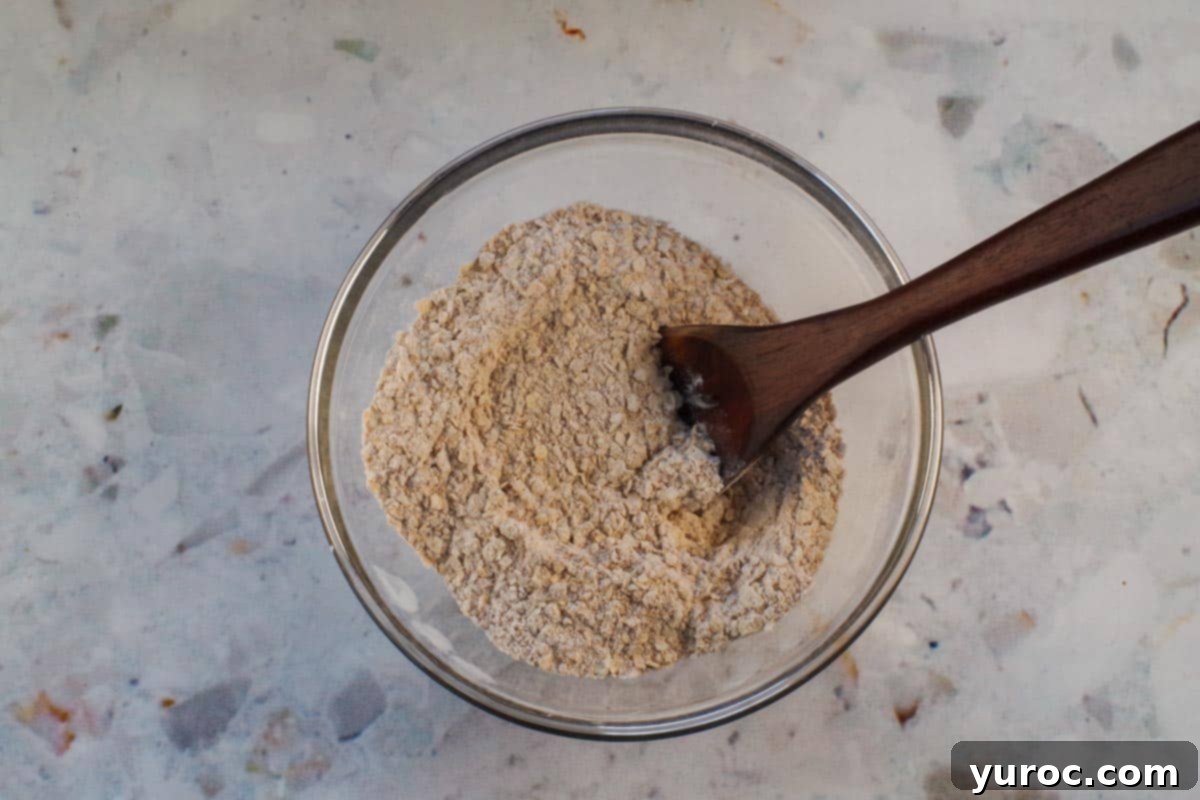 Dry topping ingredients mixed together in sepaarte glass bowl with wooden spoon.