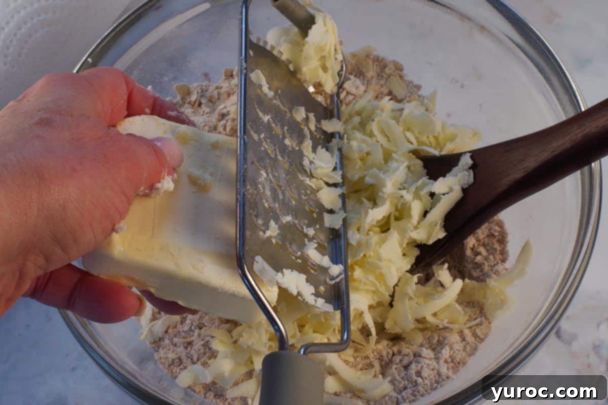 Frozen butter being cut into dry mixture with a cheese grater.