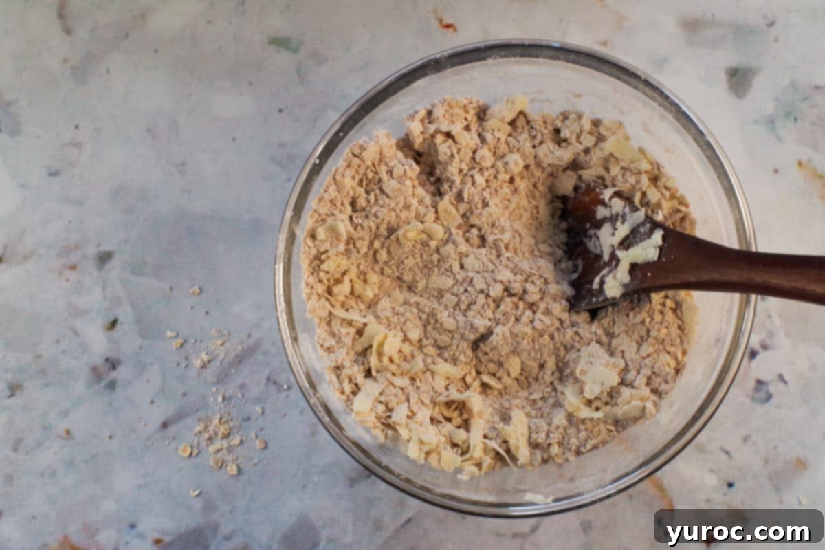 Grated butter being stirred into dry mixture.