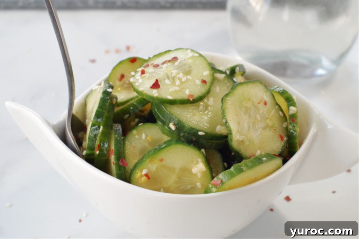 Instant Cucumber Kimchi 2 Quick Kimchi pickle in white bowl on grey marble counter surface with glass vinegar container in background
