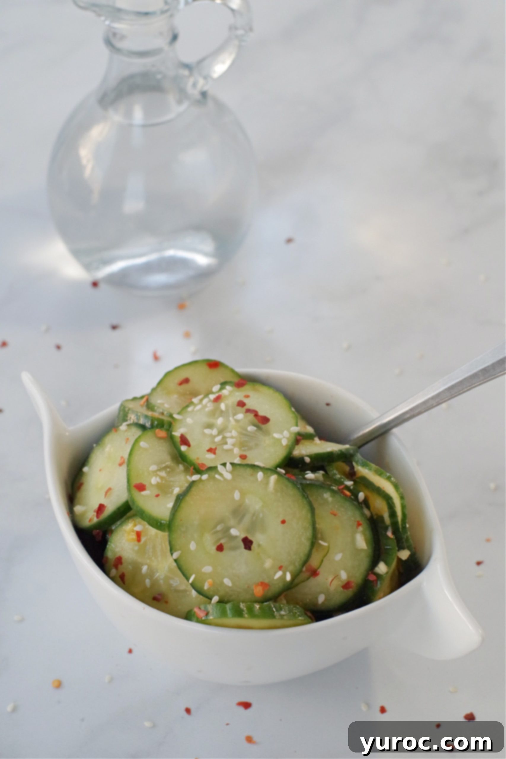 Instant Cucumber Kimchi 5 Korean pickles cucumbers in white bowl on grey marble counter surface with glass vinegar container in background