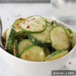 Instant Cucumber Kimchi 6 kimchi pickle in white bowl on grey marble counter surface with glass vinegar container in background