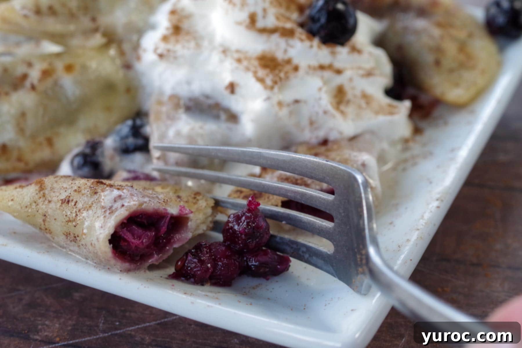 A fork cutting into a Saskatoon berry perogy, showing the rich purple filling inside
