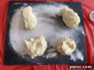 Perogy dough divided into four sections on a cutting board, ready for rolling