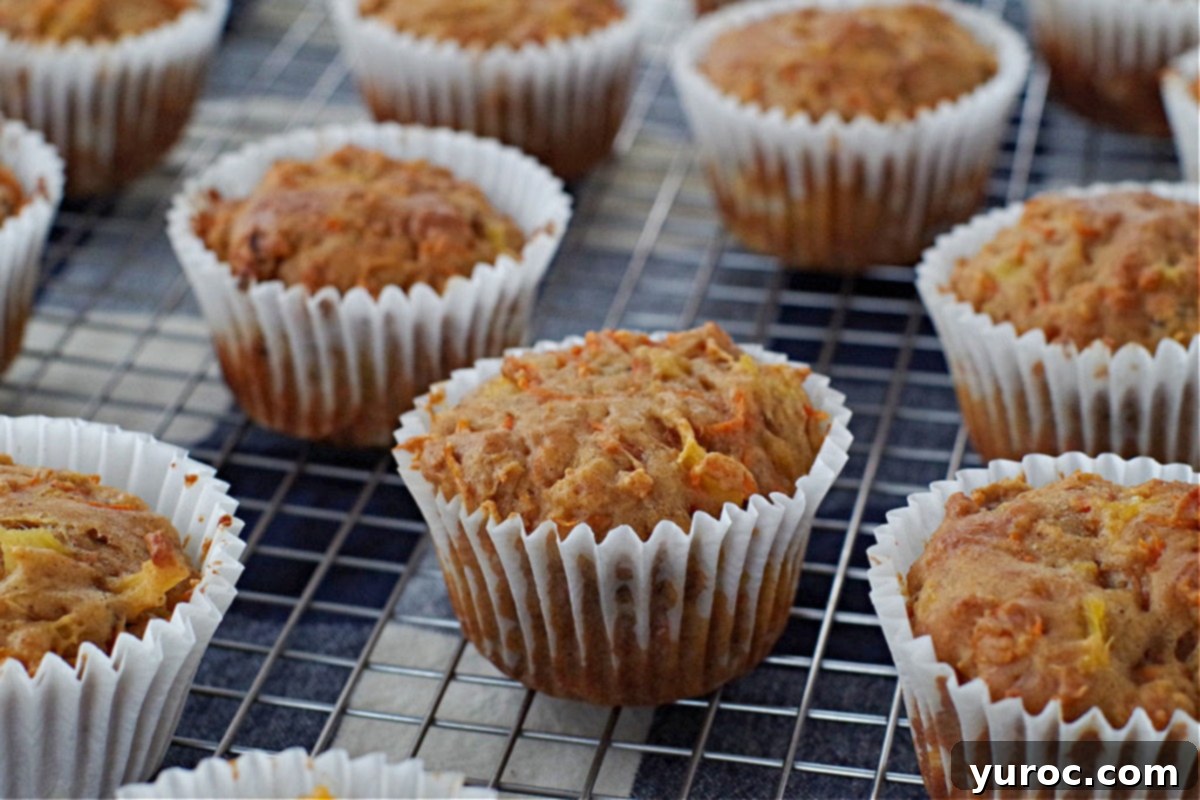 Sunshine Carrot Pineapple Muffins 3 Freshly baked carrot muffins cooling on a wire rack, steam gently rising, highlighting their fluffy texture.