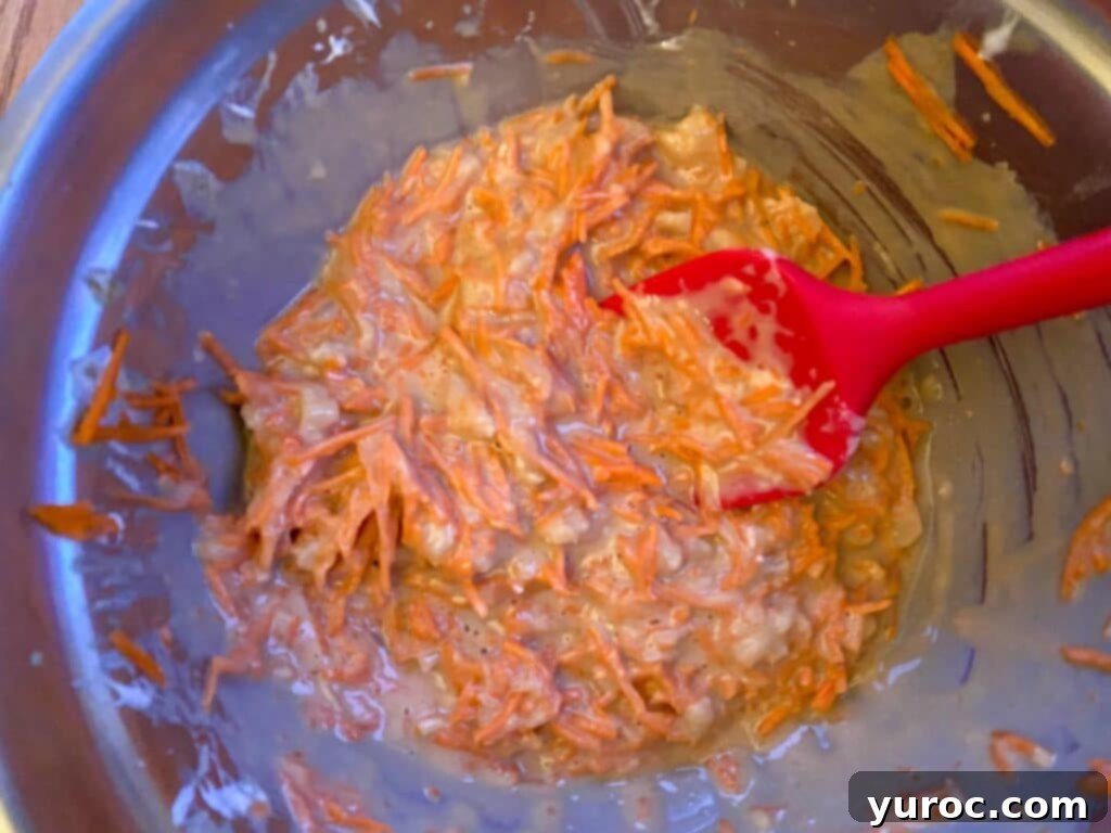 Sunshine Carrot Pineapple Muffins 5 A close-up shot of wet ingredients like oil, yogurt, sugar, and vanilla mixed thoroughly in a bowl, showing a smooth, creamy consistency.