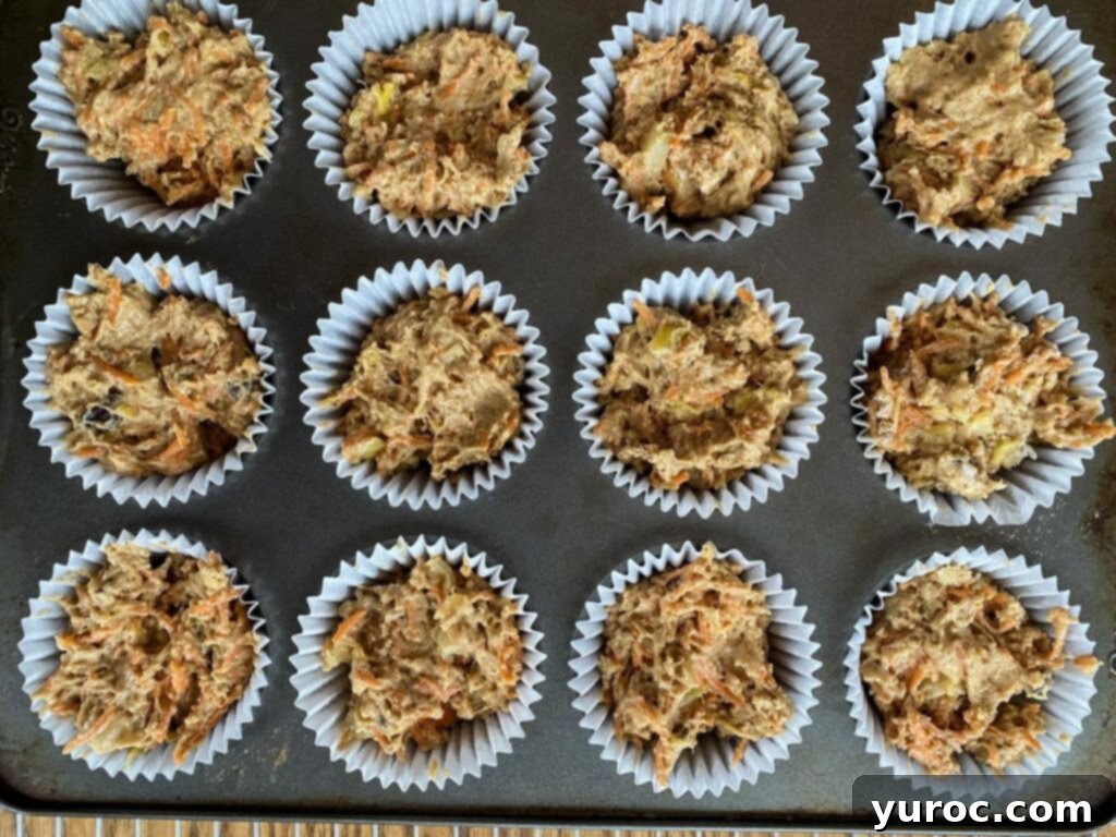 Sunshine Carrot Pineapple Muffins 7 Muffin batter neatly scooped into paper-lined muffin tins, ready to be placed in the preheated oven for baking.
