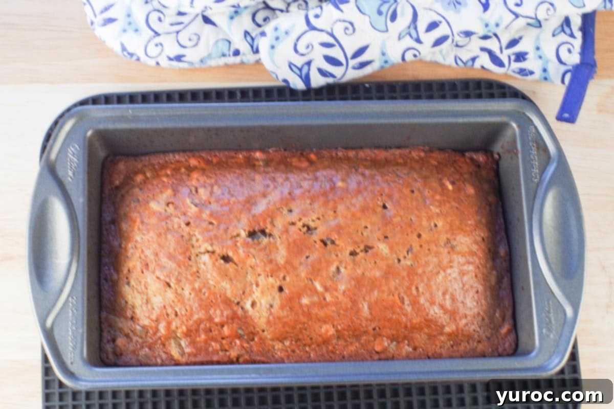 date nut loaf baked in a pan on trivet with oven mitts in background