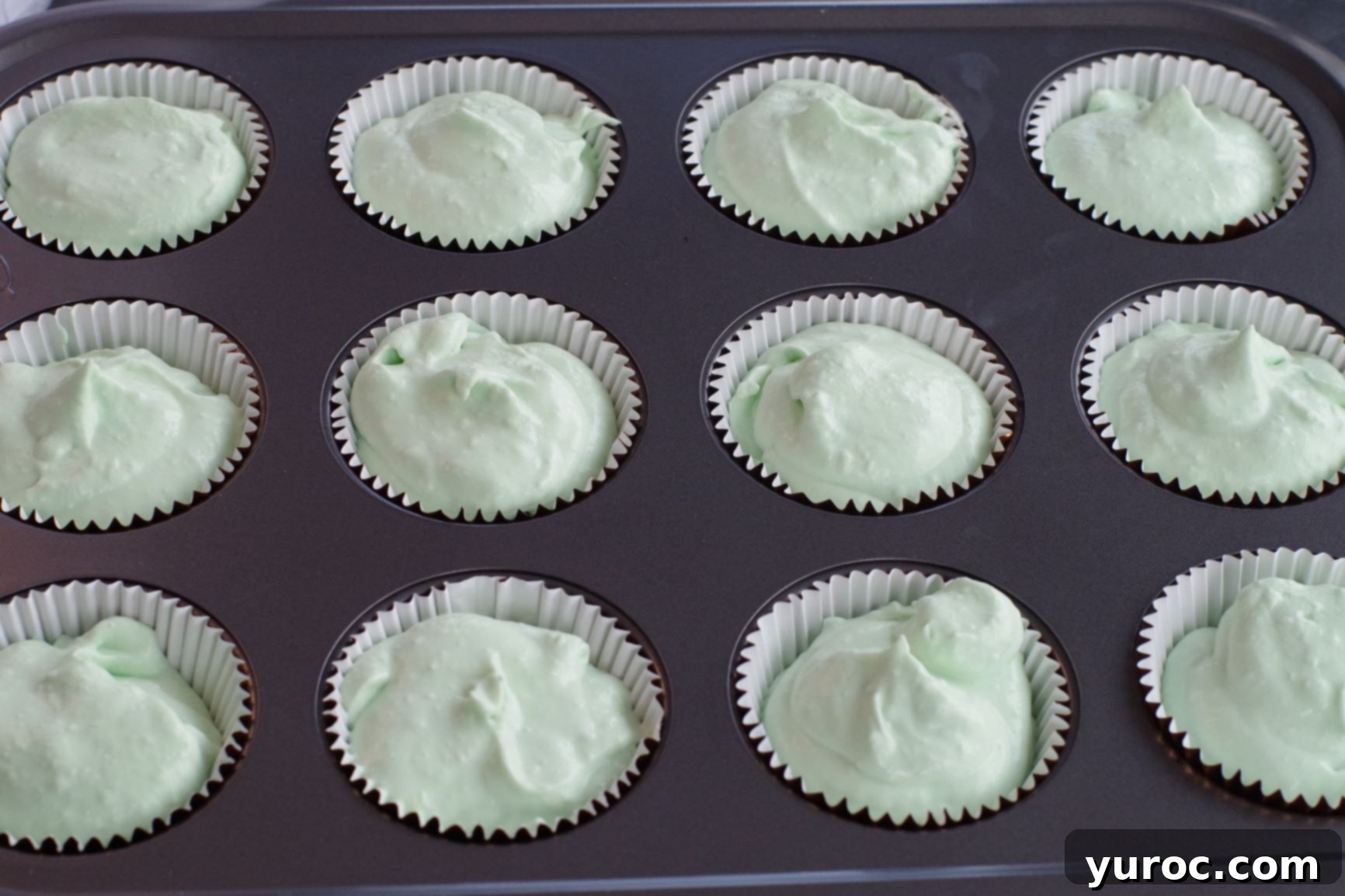 Effortless No-Churn Ice Cream Cupcakes 6 green ice cream filling being spooned into cupcake liners