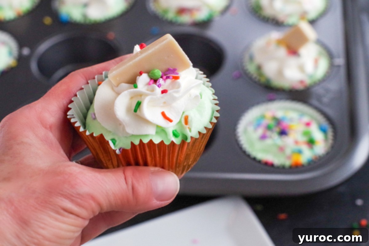 Effortless No-Churn Ice Cream Cupcakes 9 green ice cream cupcake being held up