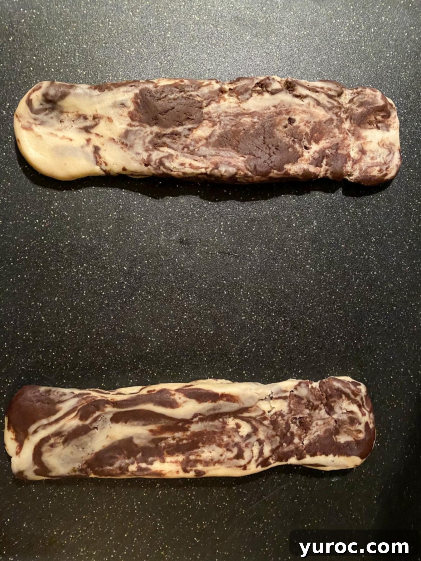 2 logs of marbled dough on a cutting board.