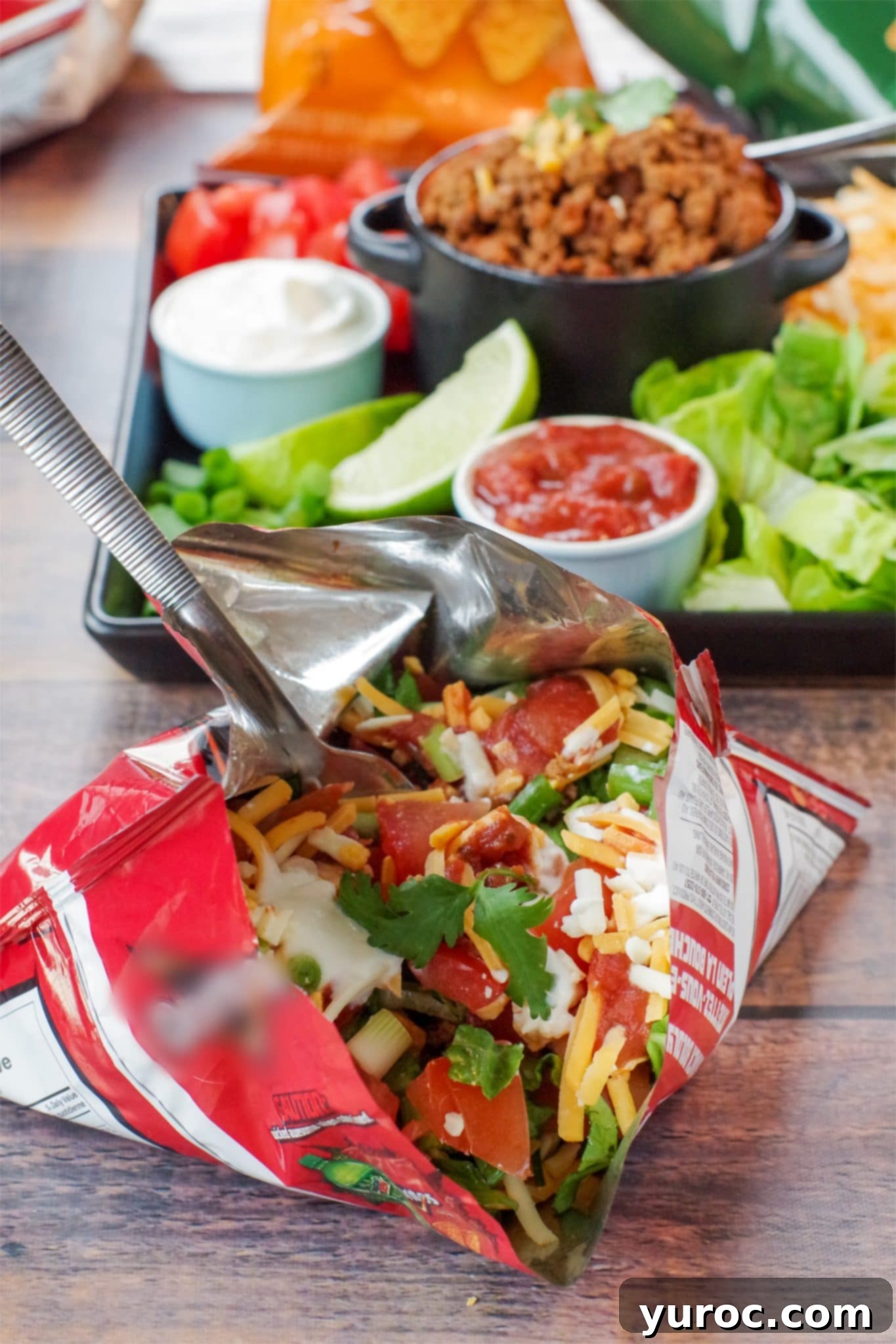 walking tacos in a bag in front and tray of taco meat and fixings in background