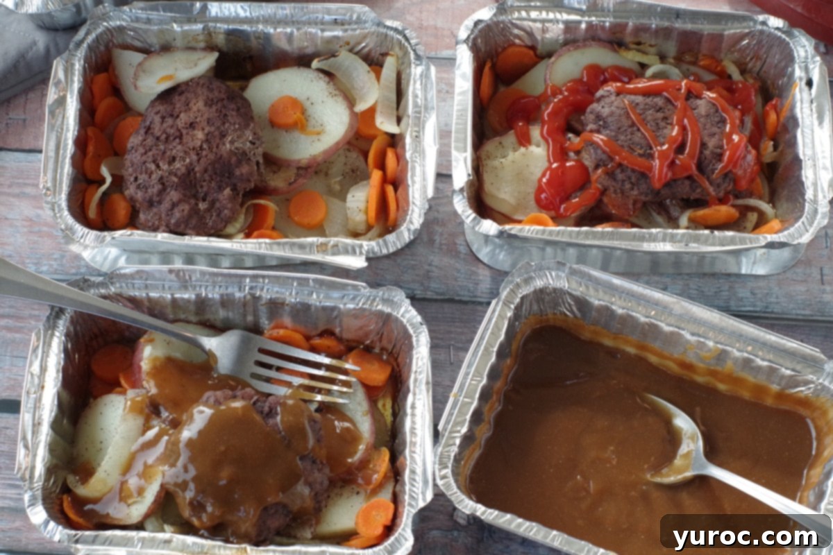 4 hamburger foil packets in aluminum foil containers with potatoes, carrots, onions and hamburgers, on wooden surface