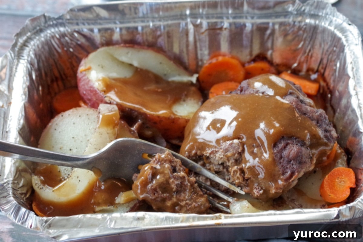 hobo dinner foil packet with fork cutting into hamburger patty