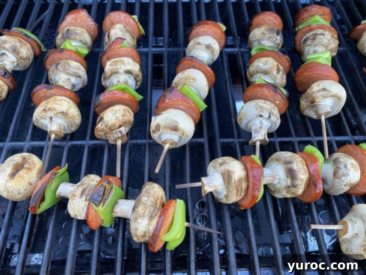 grilled pizza toppings (pepperoni, mushrooms and green peppers ) on skewers, on a BBQ grill