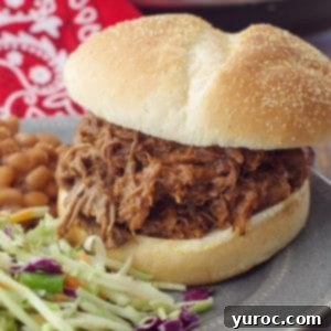 beef on a bun on a grey plate with coleslaw and beans