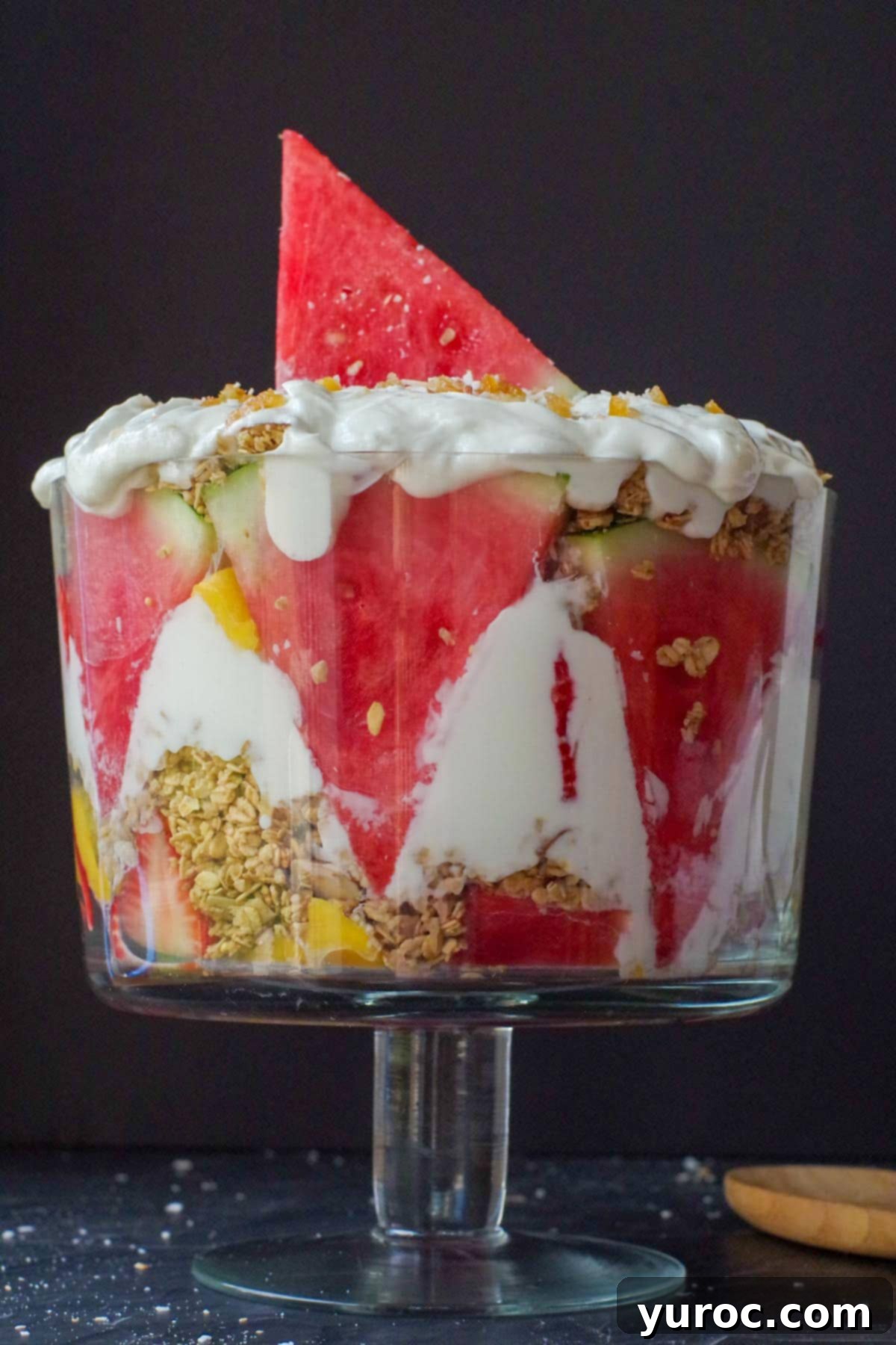 Refreshing Watermelon Granola Parfait 4 watermelon breakfast trifle in glass trifle bowl with wooden spoon on the side in front of black background