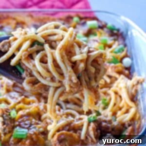 Million Dollar Spaghetti Casserole being held up on a spoon over glass casserole dish