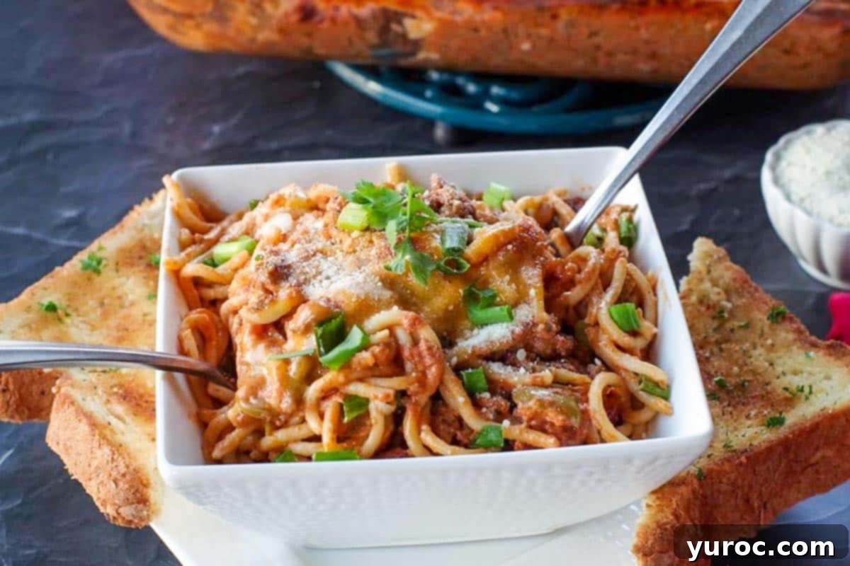Weight Watchers Spaghetti Casserole served in a white bowl with a spoon, accompanied by garlic toast.