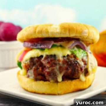 Gourmet sirloin burger with beets on a white plate with a bowl of beets in the background.