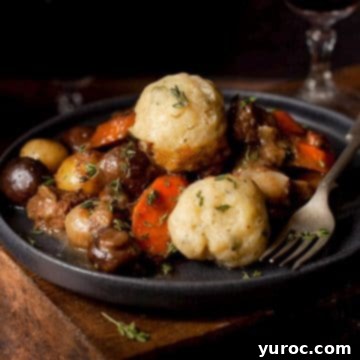 Slow-cooked beef stew and dumplings in a black bowl with a glass of wine in the background.
